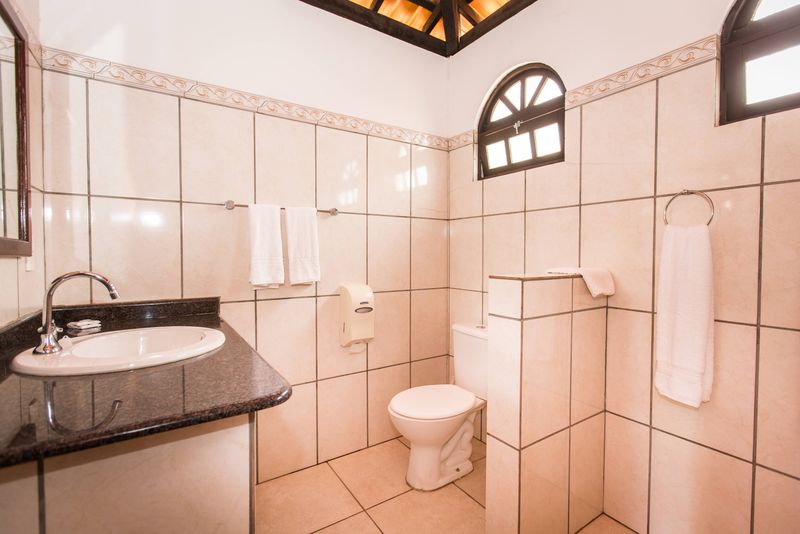 Banheiro do bangalô com pia em bancada de granito e janela em arco